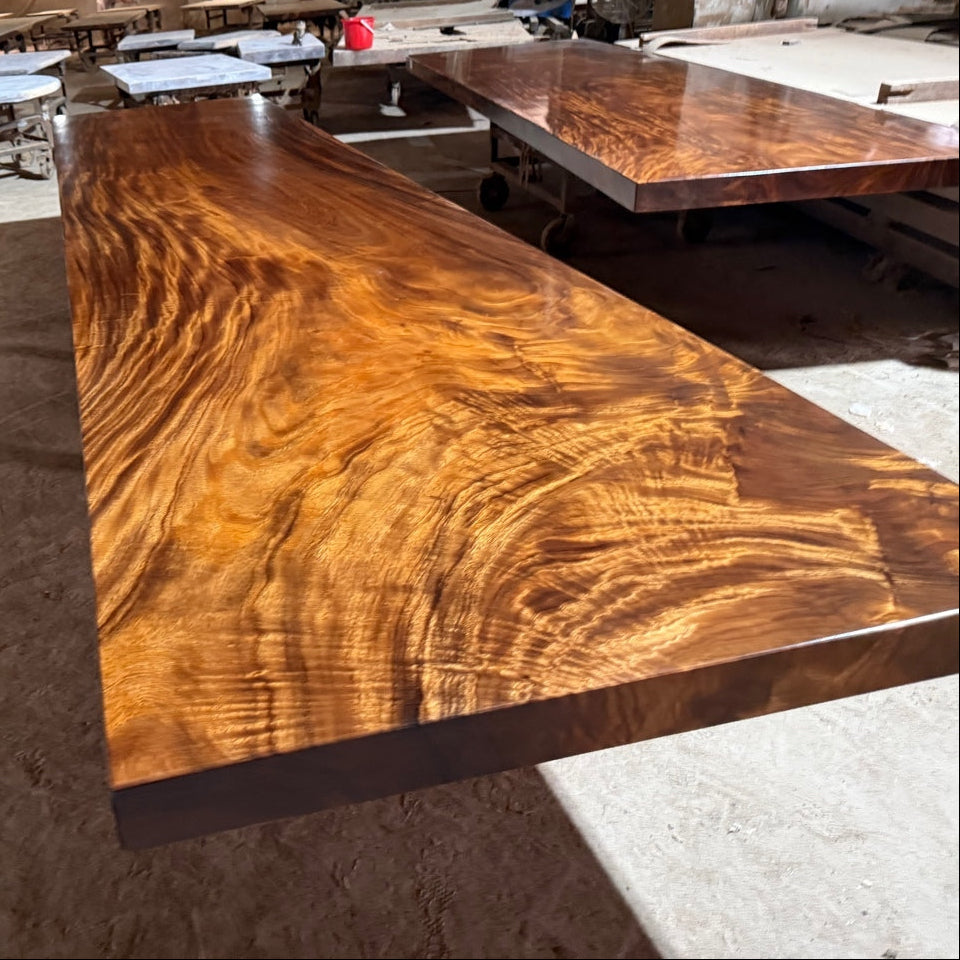 Large wooden table in a workshop setting with other tables and materials in the background.